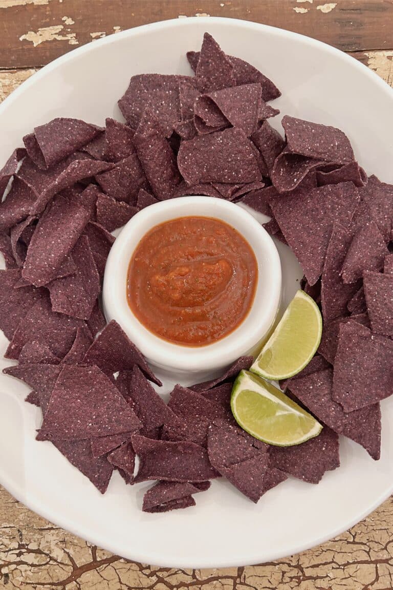 Easy Homemade Salsa Recipe in a chip and dip plate with blue corn tortilla chips and lime wedges.